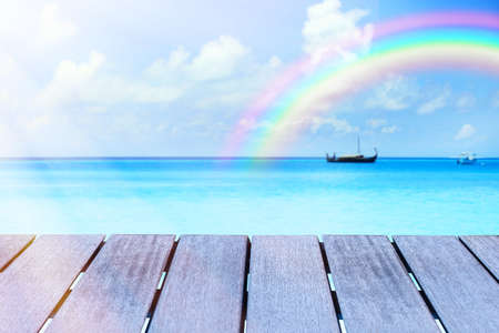 Wooden surface and beautiful seascape with rainbow on backgroundの写真素材