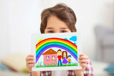 Little boy showing his drawing on tablet at homeの写真素材