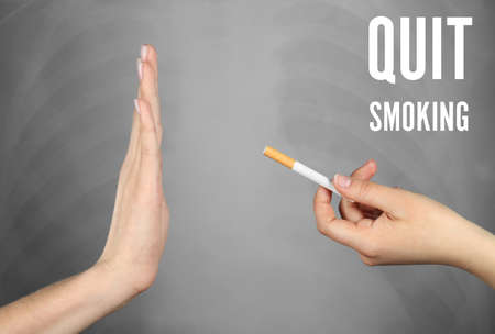 Text QUIT SMOKING and woman refusing of offered cigarette on grey backgroundの写真素材
