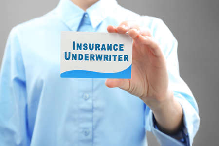 Businesswoman holding visiting card of insurance agent on grey backgroundの写真素材