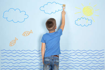 Little boy painting picture on wallの写真素材