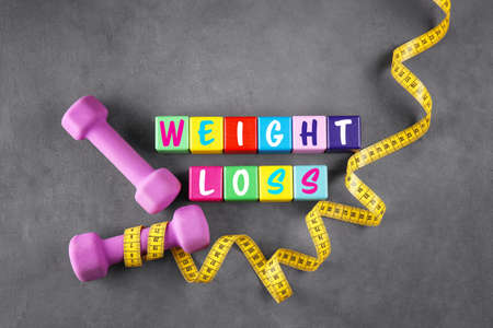 Sport concept. Text WEIGHT LOSS of colorful cubes and training equipment on gray backgroundの写真素材
