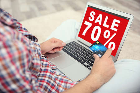 Sale concept. Man using laptop and credit card for internet online shopping at homeの写真素材