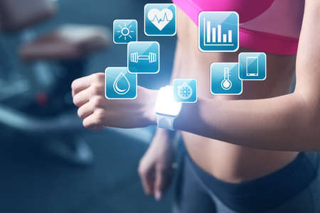Sport application concept. Young woman with fitness tracker in gymの写真素材