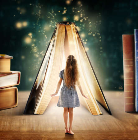Adventure story and fairy tale. Tiny girl and book with magic glowing on tableの写真素材