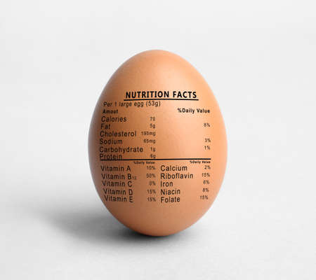 Raw egg and list of nutrition facts on white backgroundの写真素材