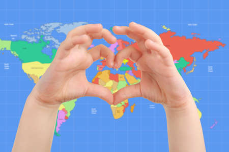 Little child holding hands in heart shape and world map on background. Earth conceptの写真素材