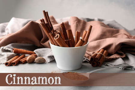Bowl with cinnamon sticks and spoon with powder on tableの写真素材