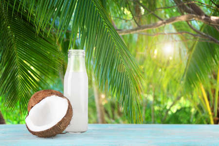 Glass bottle of coconut milk with nuts on wooden tableの写真素材