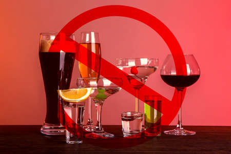 Different alcohol drinks in glasses with STOP sign on red backgroundの写真素材