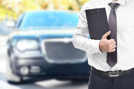 Insurance agent with clipboard and car on backgroundの写真素材