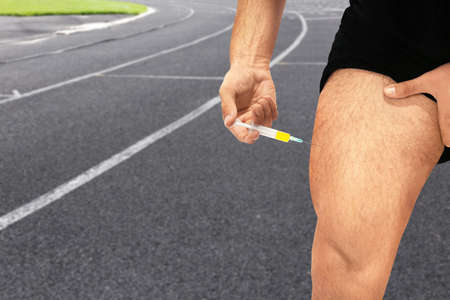 Man injecting steroids and running track on background, closeup. Sport and doping conceptの写真素材