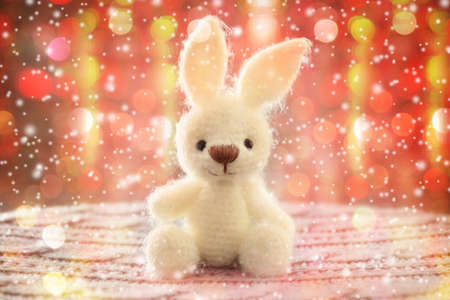 Knitted toy bunny on Christmas lights background. Holidays celebration conceptの写真素材