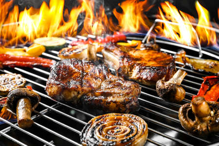 Delicious steaks with vegetables on grilling grid and flame, closeupの写真素材