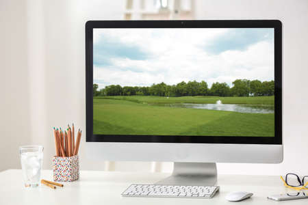 Workplace with computer monitor and wallpaper of landscape on screenの写真素材