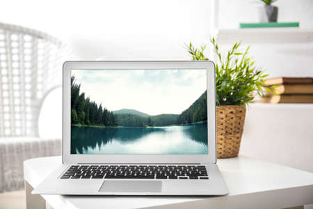 Workplace with laptop and wallpaper of landscape on screenの写真素材