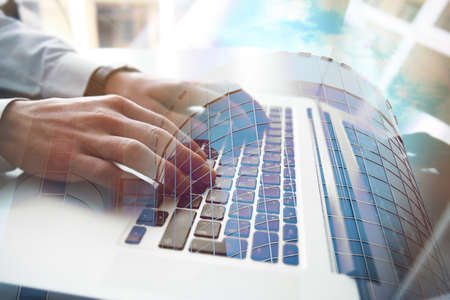 Concept of consulting. Double exposure of cityscape and businessman working with laptopの写真素材