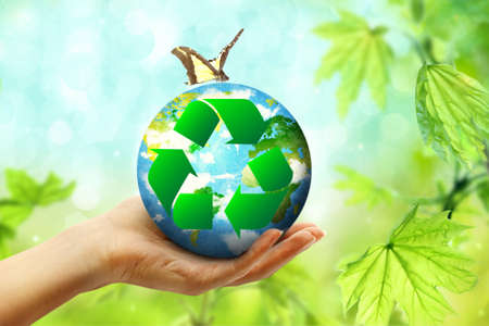 Female hand holding globe and sign of recycling on blurred background. Ecology and environment conservationの写真素材