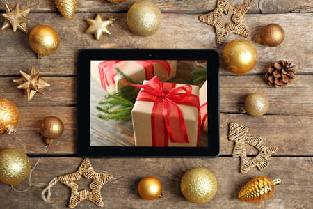 Tablet and festive decor on wooden background. Boxing day conceptの写真素材