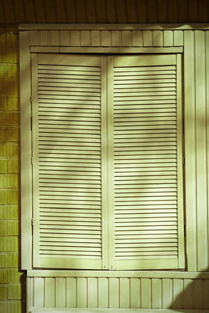 Window with closed blinds on green buildingの写真素材