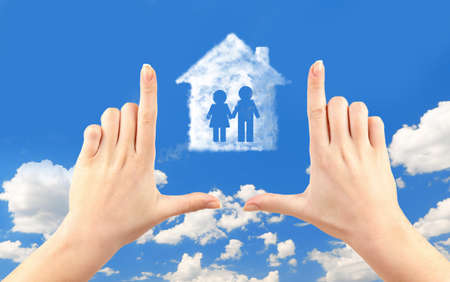 Female hands and house shape cloud on sky backgroundの写真素材