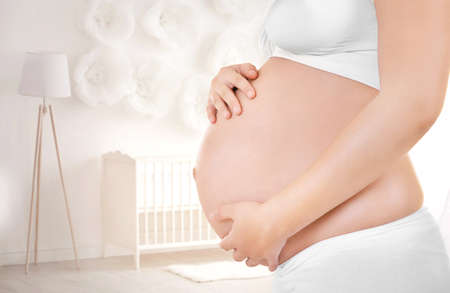 Young pregnant woman in children's room, closeupの写真素材