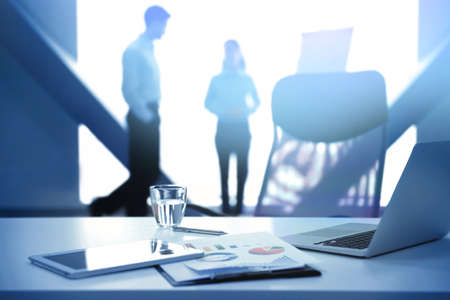 Workplace with devices and documents and people on backgroundの写真素材