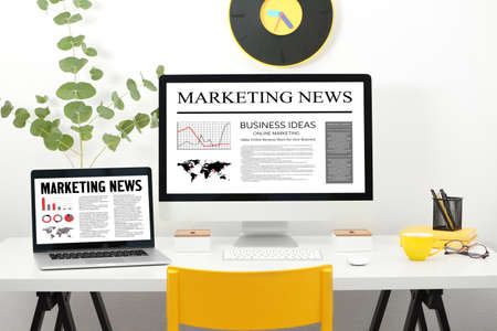 Office workplace with modern laptop and computer. Marketing news on screensの写真素材
