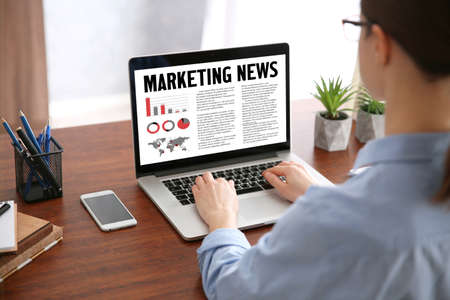 Woman reading marketing news on laptop in officeの写真素材