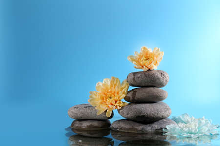 Stack of spa stones with flowers on blue backgroundの写真素材