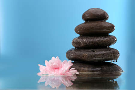 Stack of spa stones with flower on blue backgroundの写真素材