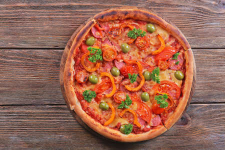 Tasty pizza with sausage and vegetables on wooden table backgroundの写真素材