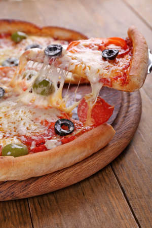 Pizza with cheese on board and wooden table backgroundの写真素材