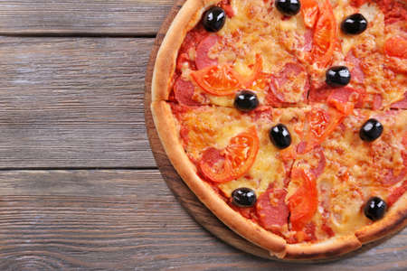 Delicious Italian pizza with black olives on wooden table backgroundの写真素材