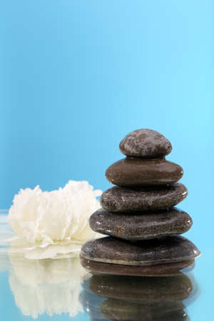 Stack of spa stones with flower on blue backgroundの写真素材