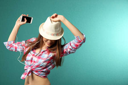 Young woman with headphones on turquoise backgroundの写真素材