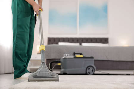Professional janitor removing dirt from Janitor Cleaning Carpet With Vacuum