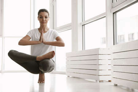 Young woman practicing toe stand asana in yoga studio. Padangusthasana ...