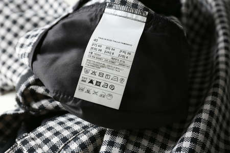 Clothing label with size and care instructions on checkered garment, closeupの写真素材