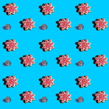 Seamless background with gingerbread in the form of snowflakes, fir cones on a vivid blue background. Hard shadows.Abstract art christmas background. Minimal print concept. Flat lay food.の写真素材