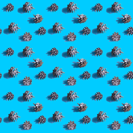 Seamless background with fir cones on a vivid blue background.Hard shadows. Abstract Christmas art...