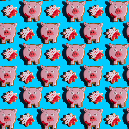 Seamless background with gingerbread in the form of pig and snowflakes on a vivid blue background. Hard shadows. Abstract art christmas background. Minimal print concept. Flat lay food.の写真素材