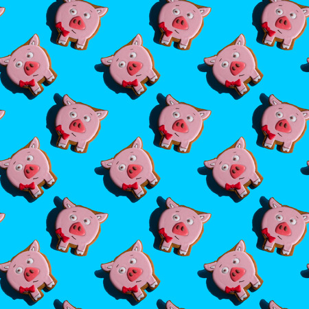 Seamless background with gingerbread in the form of pig on a vivid blue background. Hard shadows. Abstract art christmas background. Minimal print concept. Flat lay food.の写真素材