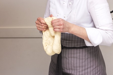 Baking concept. Hard working women prepares pastry by himself, kneads dough on wooden counter with flour and rolling pin. Women cook bakes bread or delicious bun or pasta.の写真素材