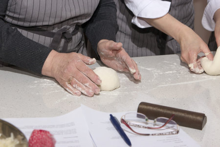 Baking concept. Hard working women prepares pastry by himself, kneads dough on wooden counter with...