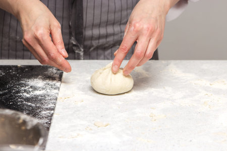 Baking concept. Hard working women prepares pastry by himself, kneads dough on wooden counter with...