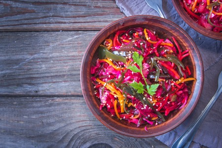 Dietary salad with sea kale, carrots, beets and sesame, sprinkled with olive oil in rustic ceramic bowl on wooden background. Detox concept.の写真素材