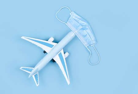 Airplane in flight with a medical mask. Concept - observance of safety on the plane. Traveling by air at social distance. Compliance with the recommendations of doctors on trips.の写真素材