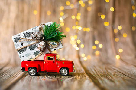 miniature car on wooden background with christmas light, holiday gift.の写真素材