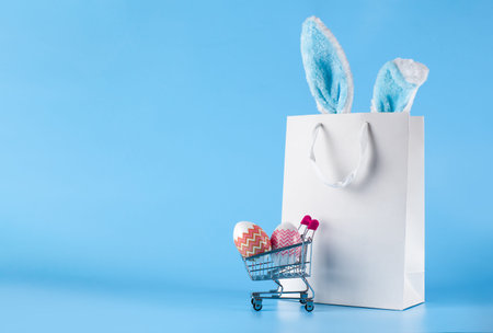 Easter banner, gift bag and shopping cart on a blue background. The concept of Easter sale,...